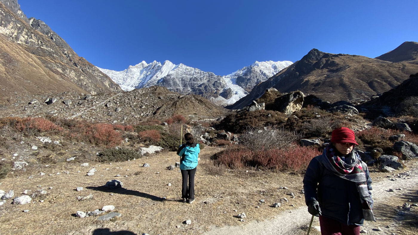 Trekkers walking on Langtang Valley trail with mountain views