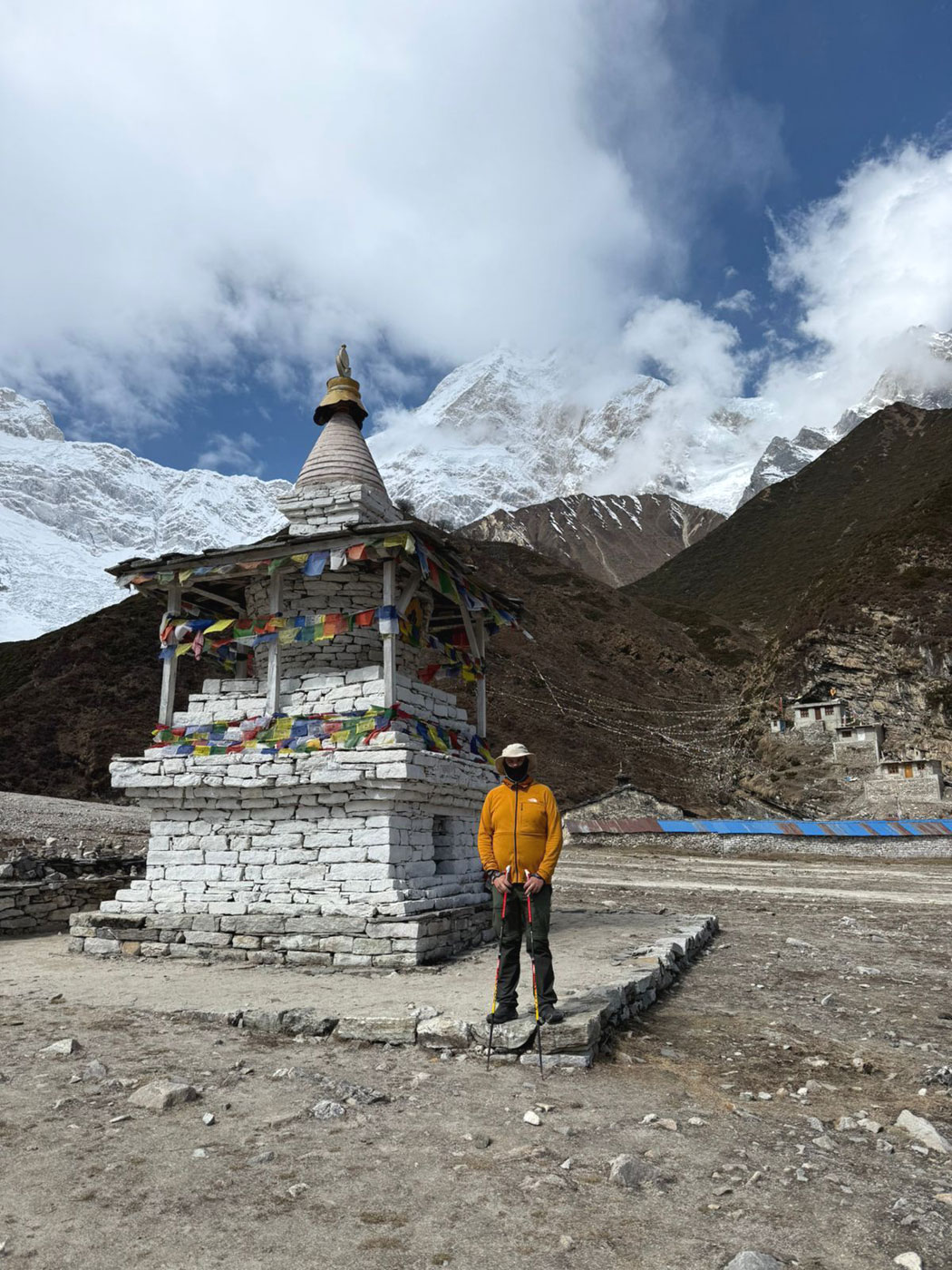 Trekkers in Buddhist chorten with prayer flags and Himalayan mountain view on Manaslu Circuit Trek