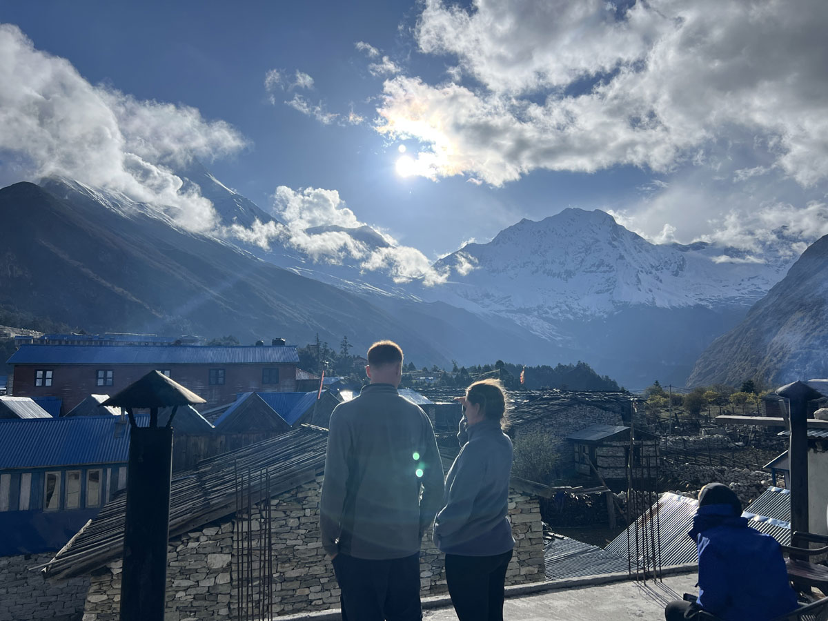 Mount Manaslu viewed from Lho village with trekkers and a traditional tea house on the Manaslu Circuit Trek