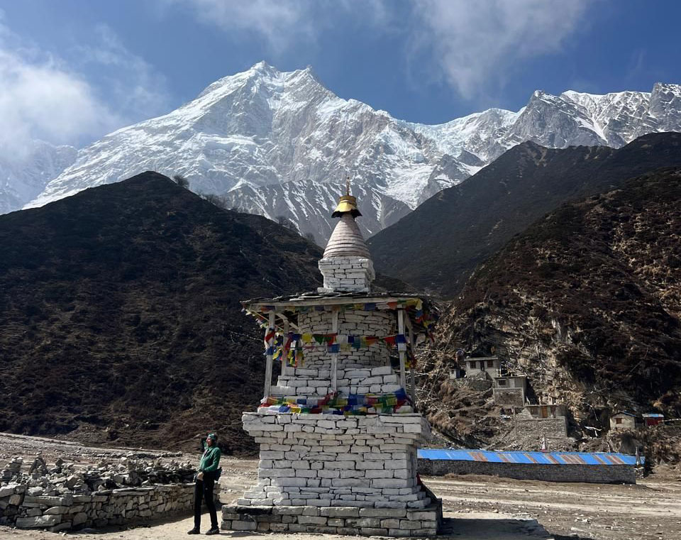 Trekker passing a chorten with Mount Manaslu in the background